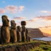 Rapa Nui Easter Island with a row of ancient Moai statues overlooking the Pacific Ocean at sunset.