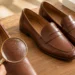 Hand checking the label and grain of a pair of brown leather shoes.