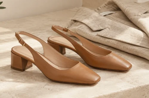 Tan leather slingback shoes with low block heels on a stone surface beside a folded linen blazer.